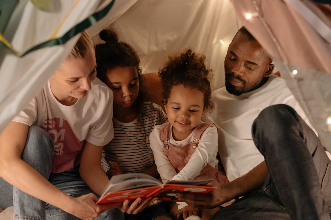A family huddles together in a tent as they camp in their very own backyard.