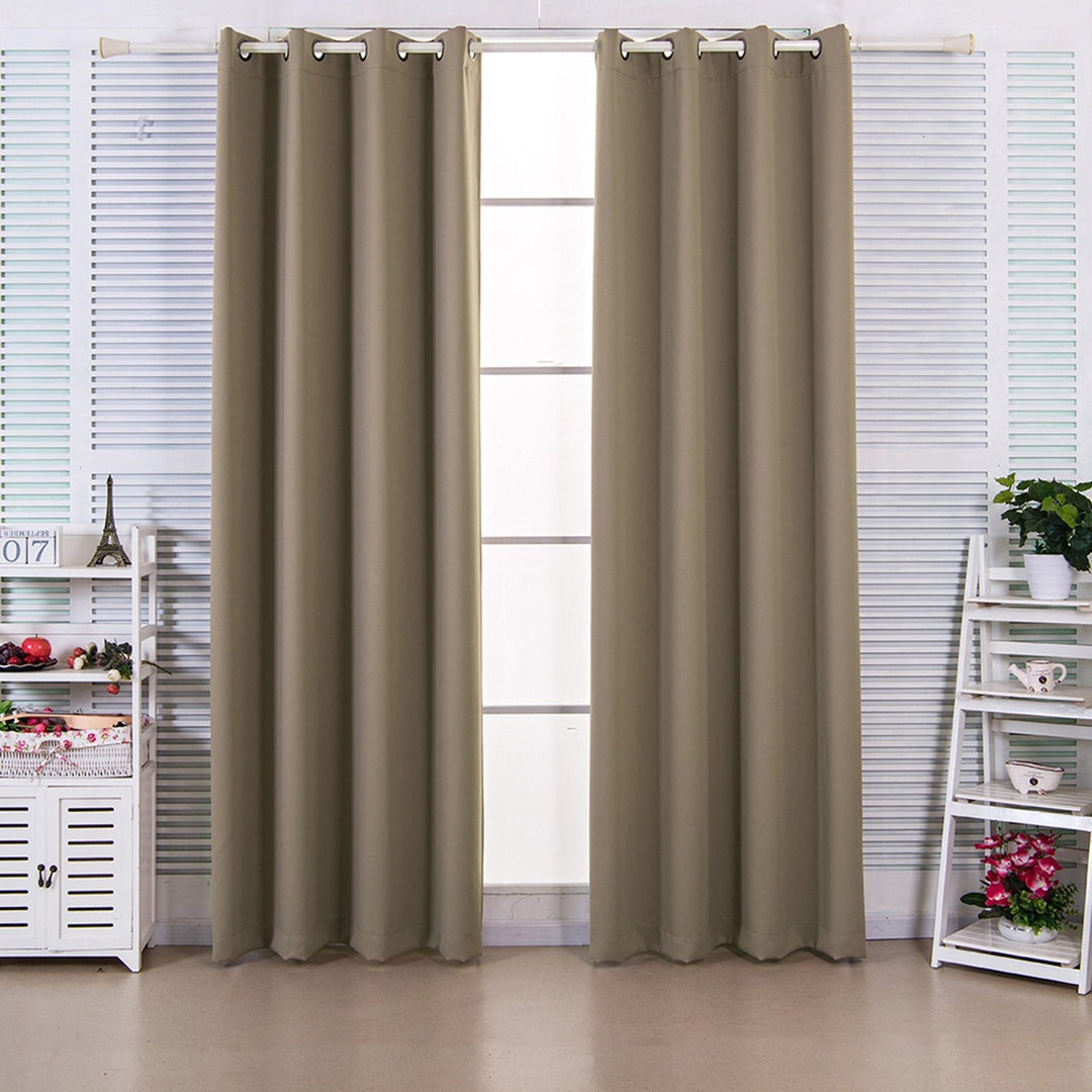 Light brown blackout curtains hang in front of a window in a white room.
