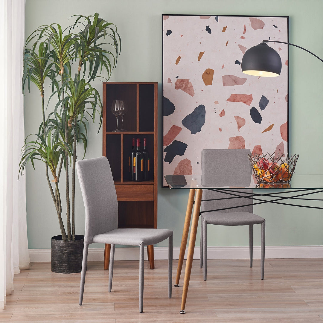 A mint green dining room features two gray teamson dining chairs around a glass top teamson dining table with light brown table legs.