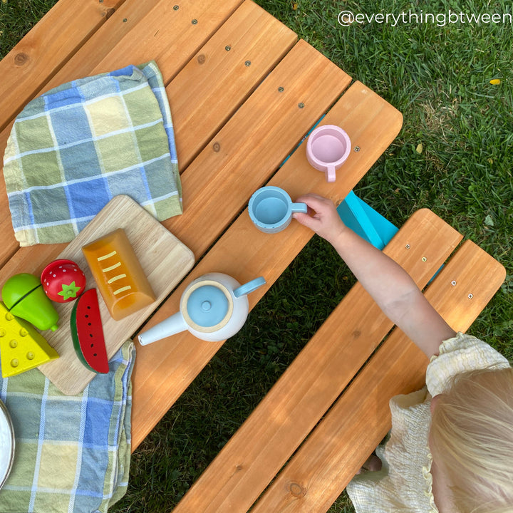The view from above of a kids picnic table with play food and dishes on the tabletop