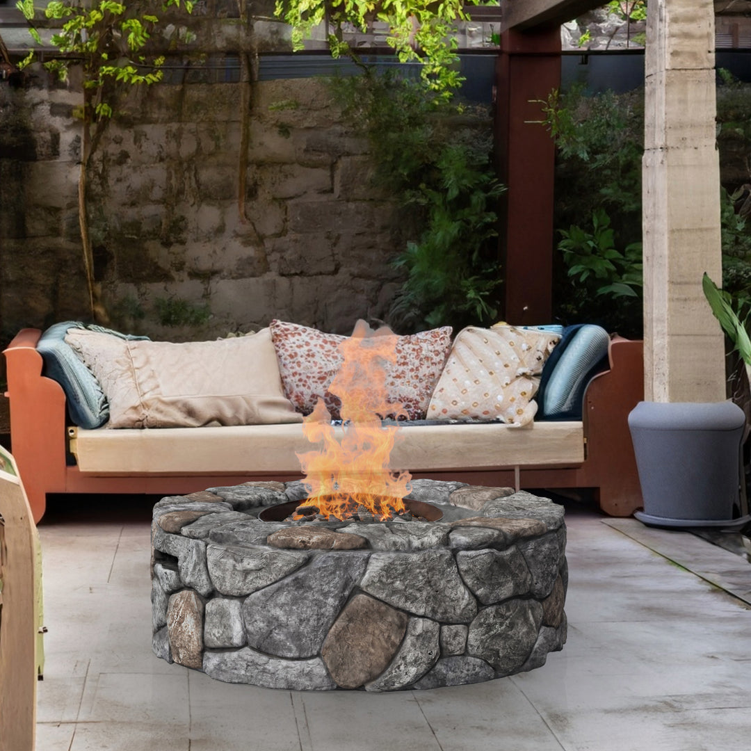 A round faux stone gas fire pit in front of an outdoor seating arrangement