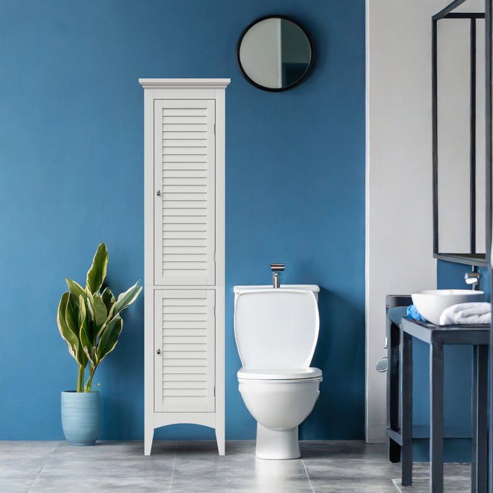 A tall white linen cabinet with faux louvered doors next to a white toilet in a blue bathroom
