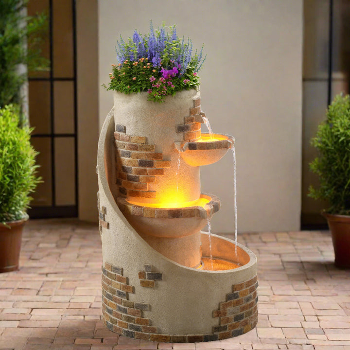 the fountain is displaying wild flowers and flowing water, plus LED lights in a brick patio