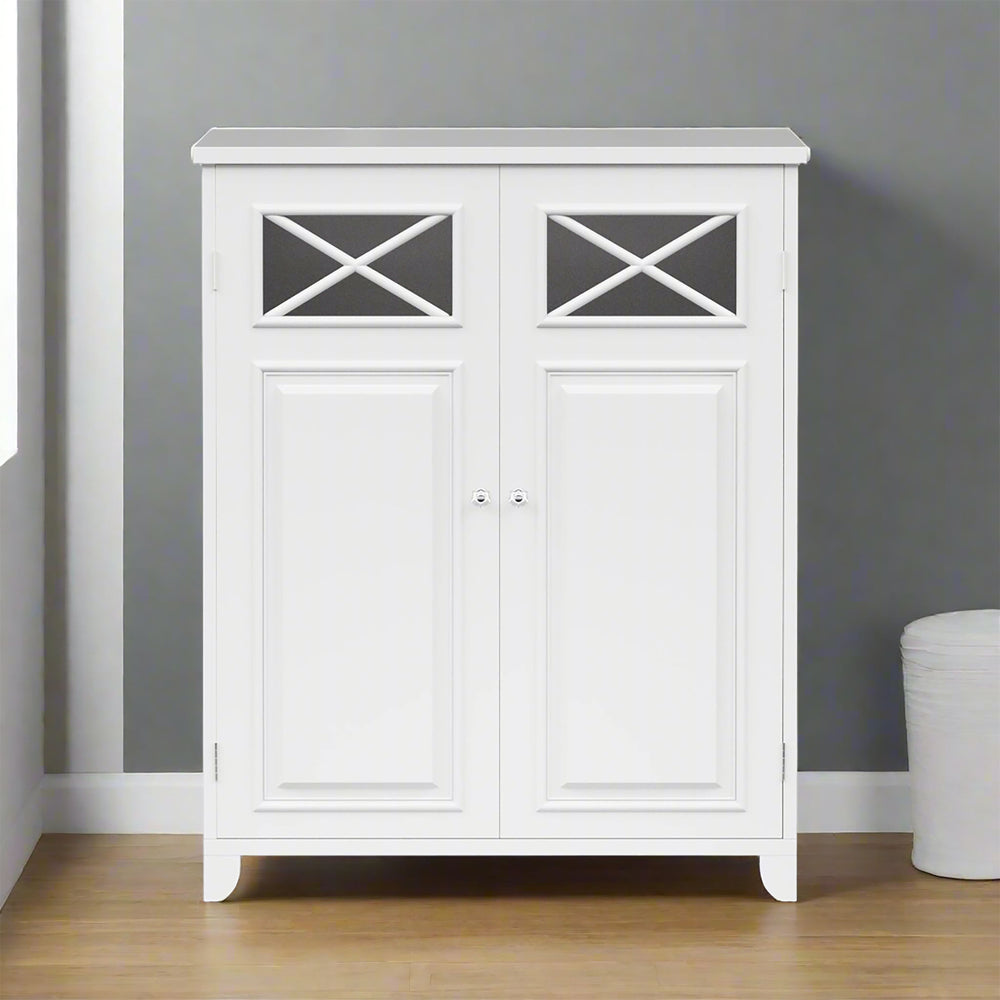 A white storage cabinet with two doors, featuring crossed detailing at the top, stands against a gray wall on a wooden floor. A small white basket is partially visible on the right.