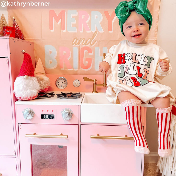 A little girl sitting on a modern pink play kitchen