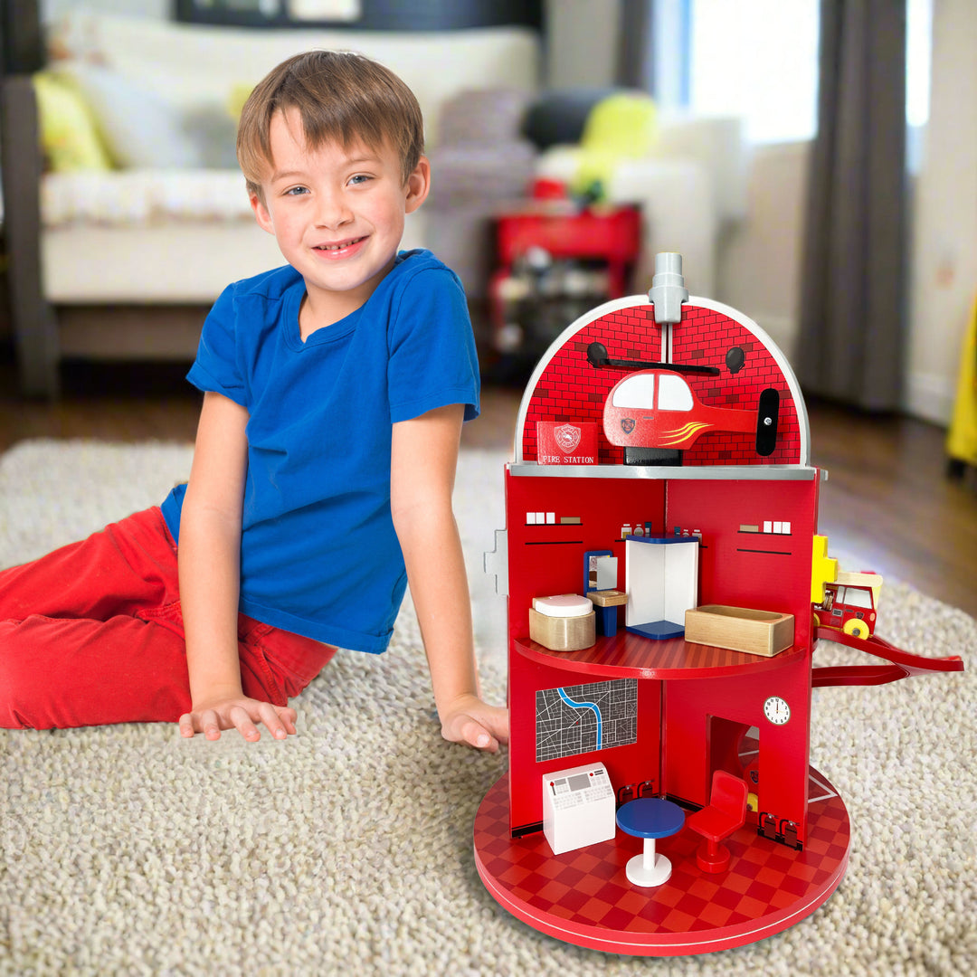 A boy sits next to his firestation in a living room.