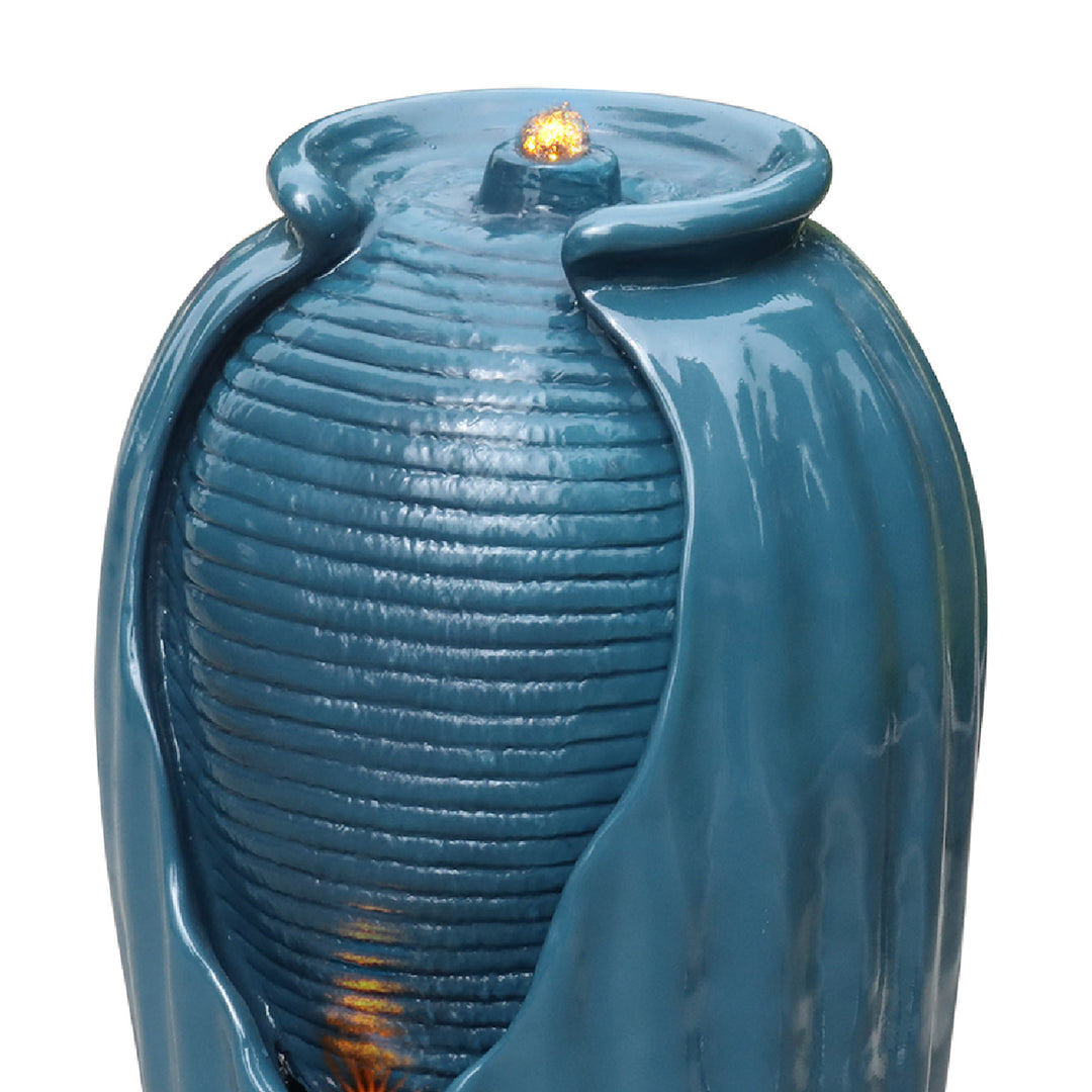 Close-up of where water flows from at the top of a blue vase-shaped water fountain 