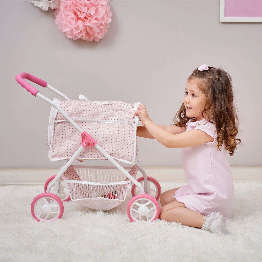 A little girl reaching into her enclosed 2-in-1 pet stroller with a detachable carrier in pink with gray polka dots.