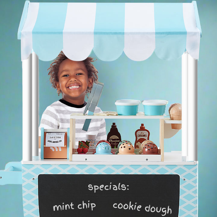 a very happy boy is ready to take your ice cream order, standing behind the cart