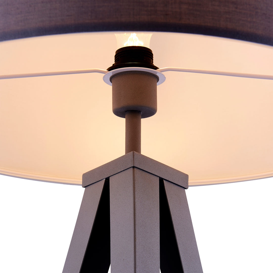 Close-up of a Teamson Home Romanza 62" Postmodern Tripod Floor Lamp with Drum Shade, Gray with a lit bulb and a brown shade on a versatile tripod-style base.