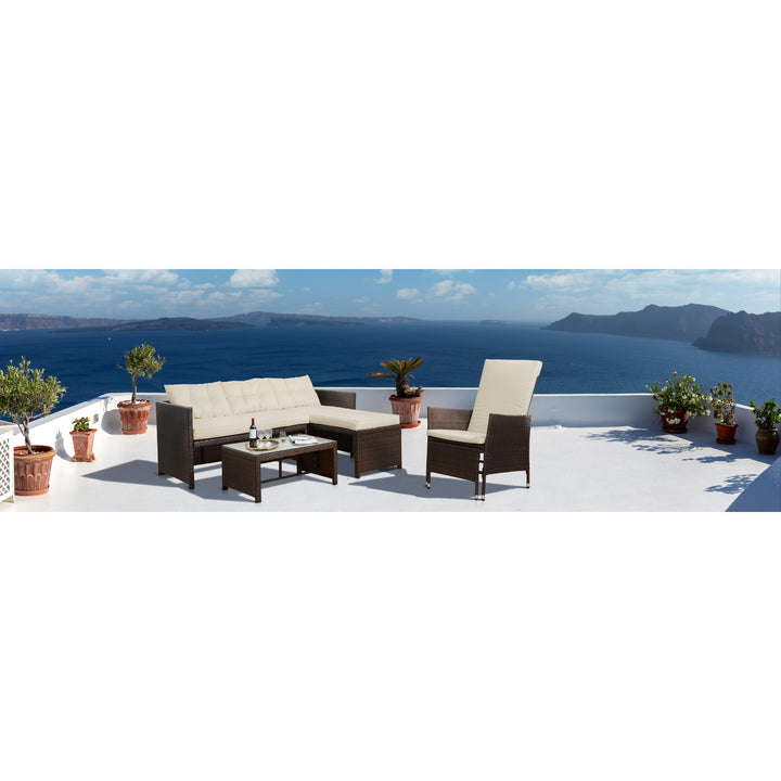 Outdoor seating area with Teamson Home Outdoor PE Rattan Patio Chair with Ottoman and Cushions, Brown/Whites and a sofa overlooking a sea view, complemented by weather-resistant cushions.