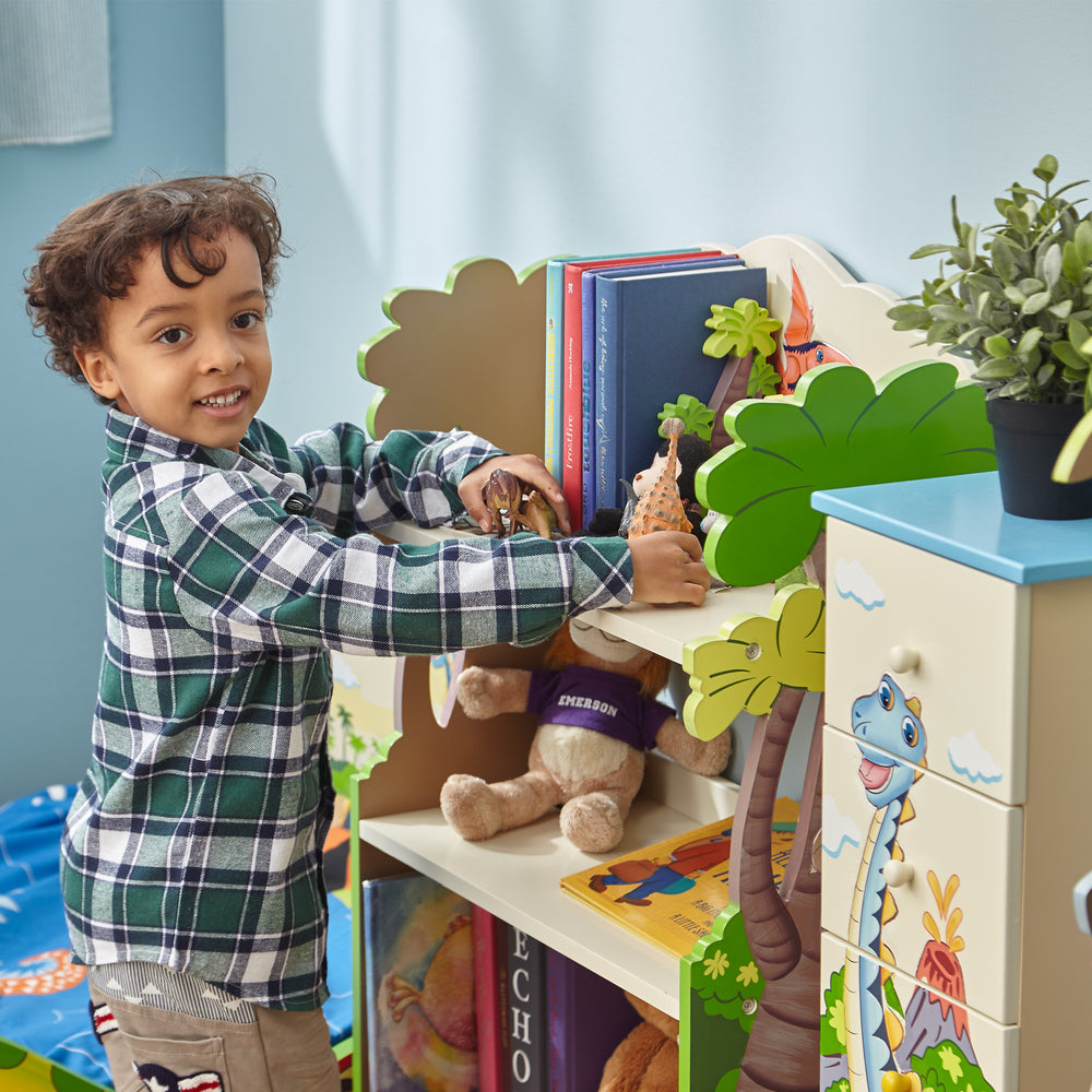 A young boy playing with his Fantasy Fields Dinosaur Kingdom Bookshelf with Storage Drawer in his room.