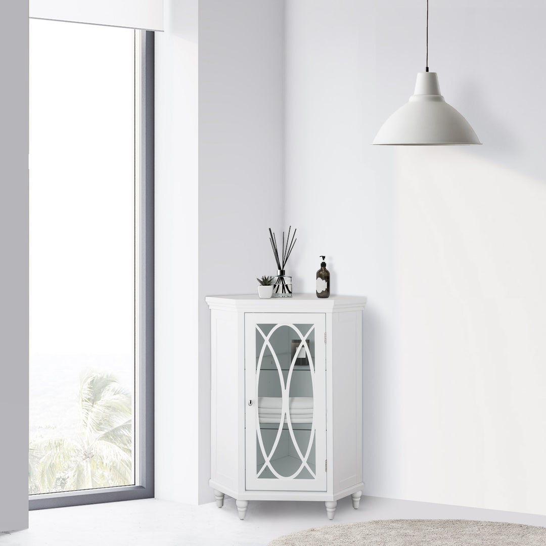 A White Teamson Home Florence Corner Floor Cabinet with lattice-designed glass panel door in the corner of a white room next to a large window