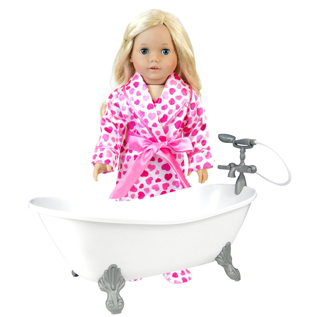 An 18" doll in a pink robe slippers is standing next to a Clawfoot Bathtub Pretend Furniture for 18" Doll included for pretend play.