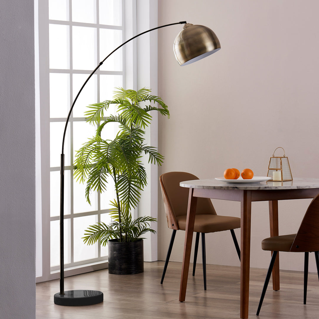 A dining room with a table and chairs and a Teamson Home Arquer Arc 68" Metal Floor Lamp with Bell Shade, Antique Brass.