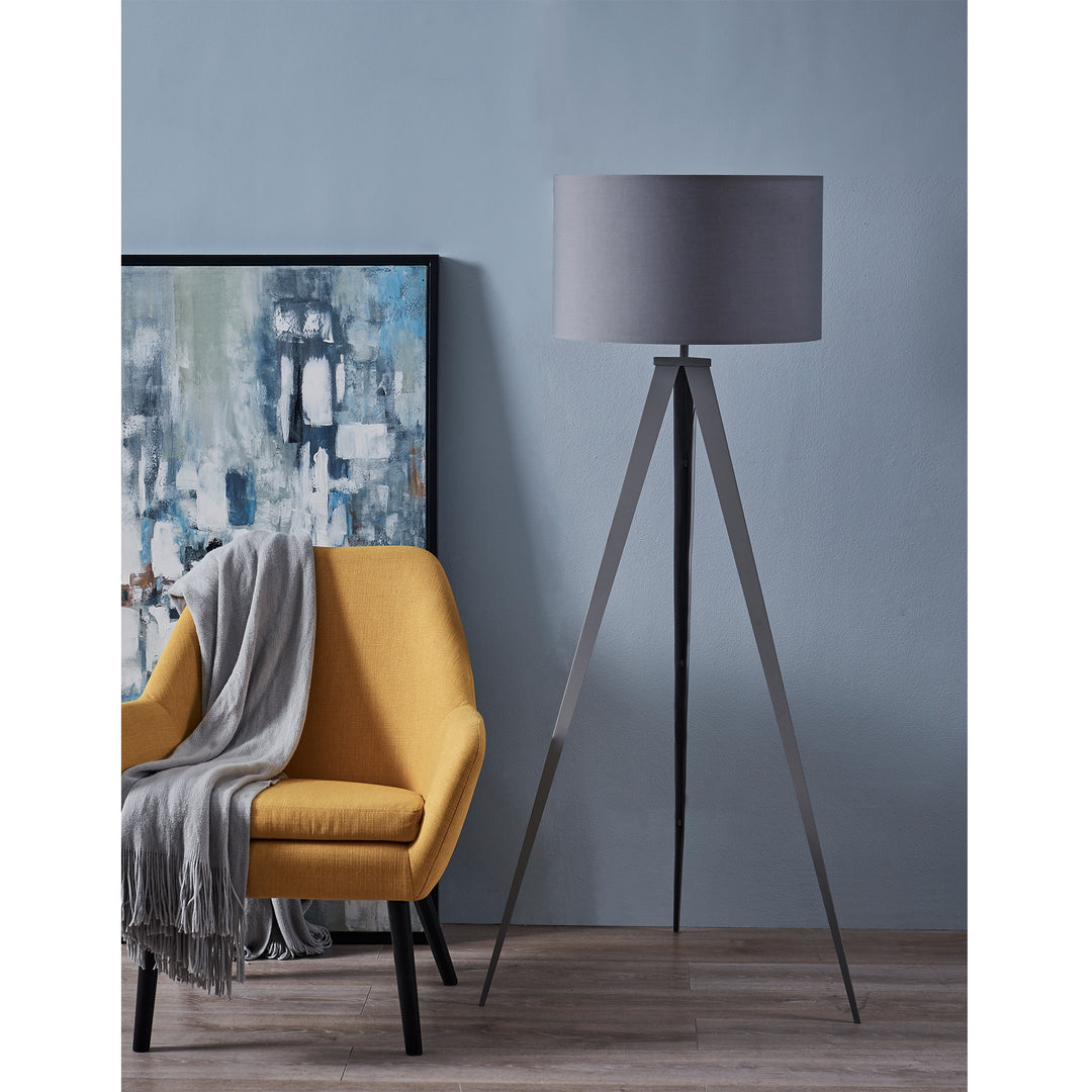 Modern interior with a yellow armchair, gray throw blanket, versatile Teamson Home Romanza 62" Postmodern Tripod Floor Lamp with Drum Shade, Gray, and abstract painting against a blue wall.