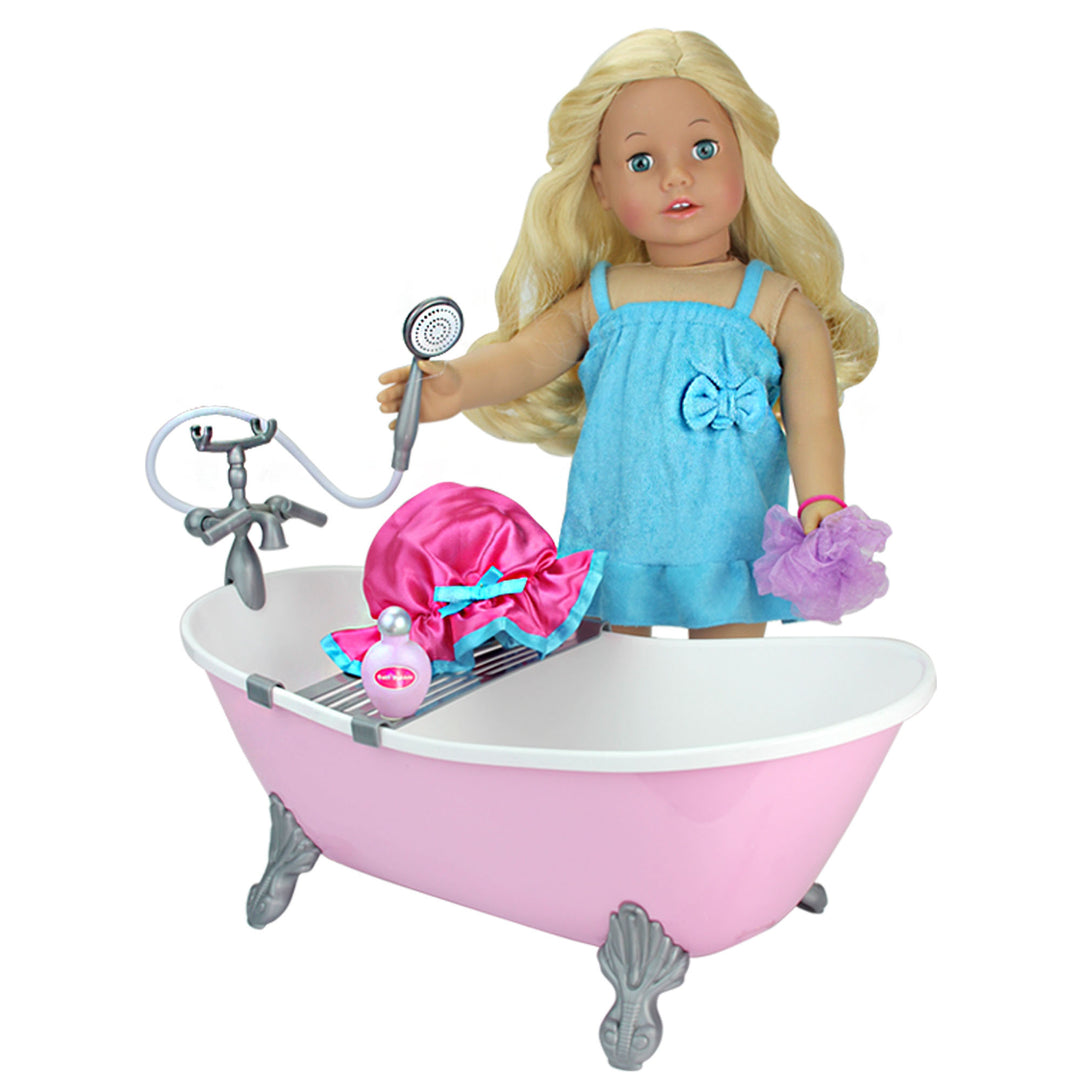 An 18" blonde doll dressed in a terry cloth holds a sprayer and a loofah in the other as she stands next to a pink bathtub.