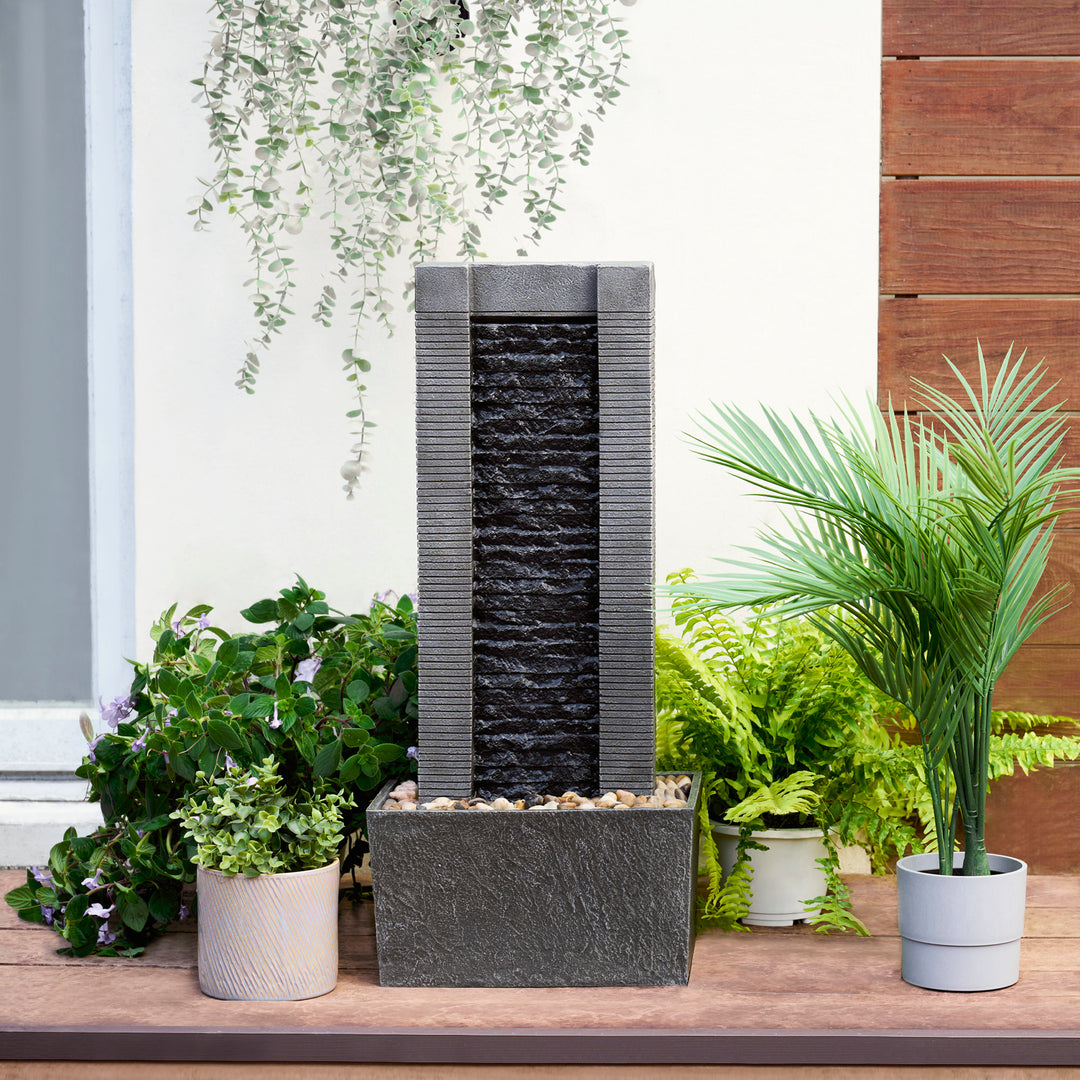 Outdoor water feature with cascading Teamson Home Demeter Outdoor Water Fountain surrounded by assorted potted plants.