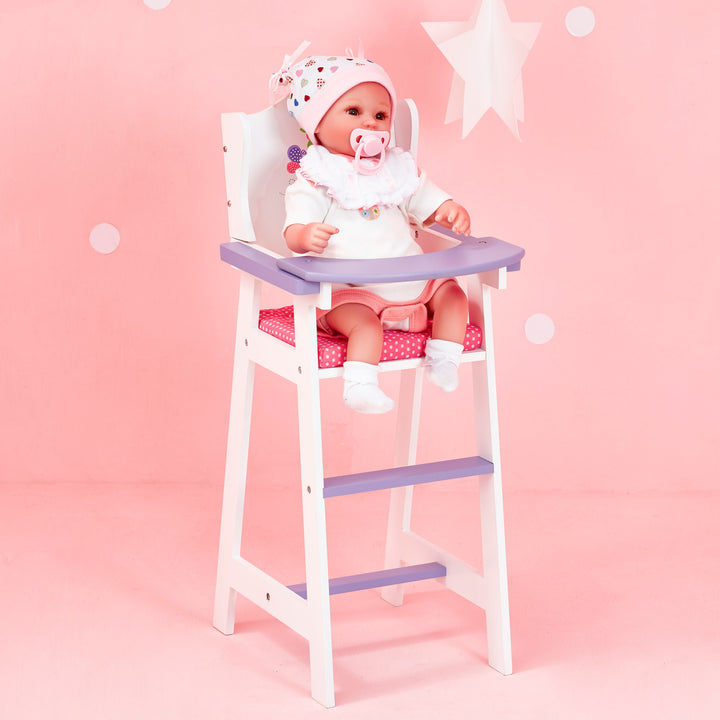 A baby doll sitting inside a highchair for dolls, white with pink cushion and purple tray