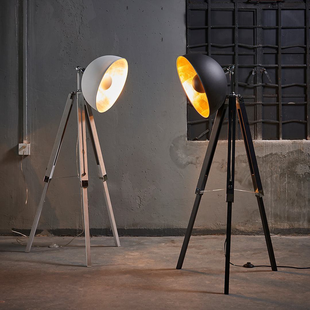 A pair of Teamson Home Fascino Modern Spotlight Tripod Floor Lamps with a white and a black lamps in an industrial setting