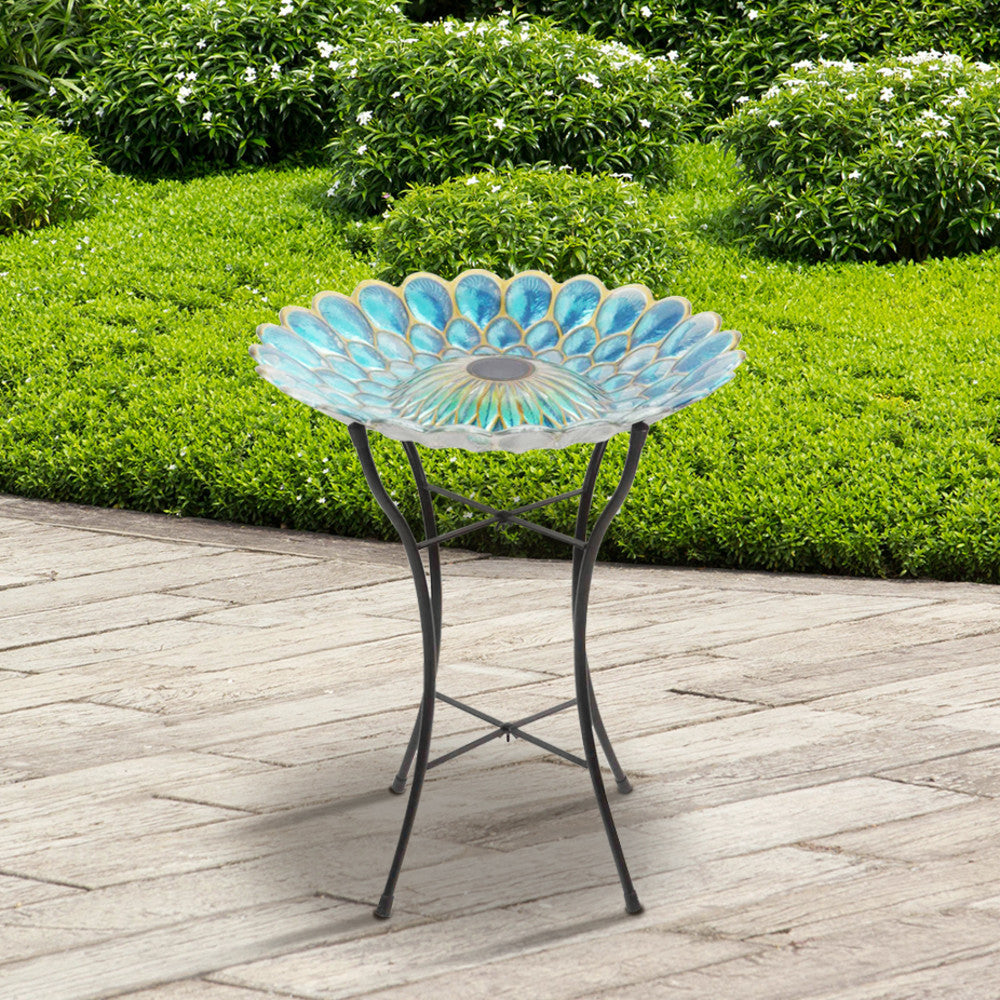 Teamson Home 18" Solar Fusion Glass Birdbath resembling a flower design, placed on an outdoor patio.