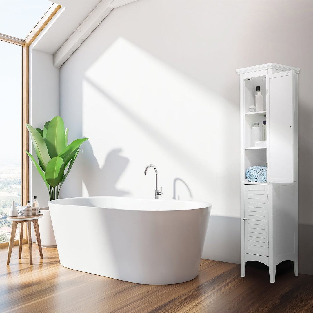 A white tower linen closet with an open door is next to a white modern bathtub in a sunlit bathroom