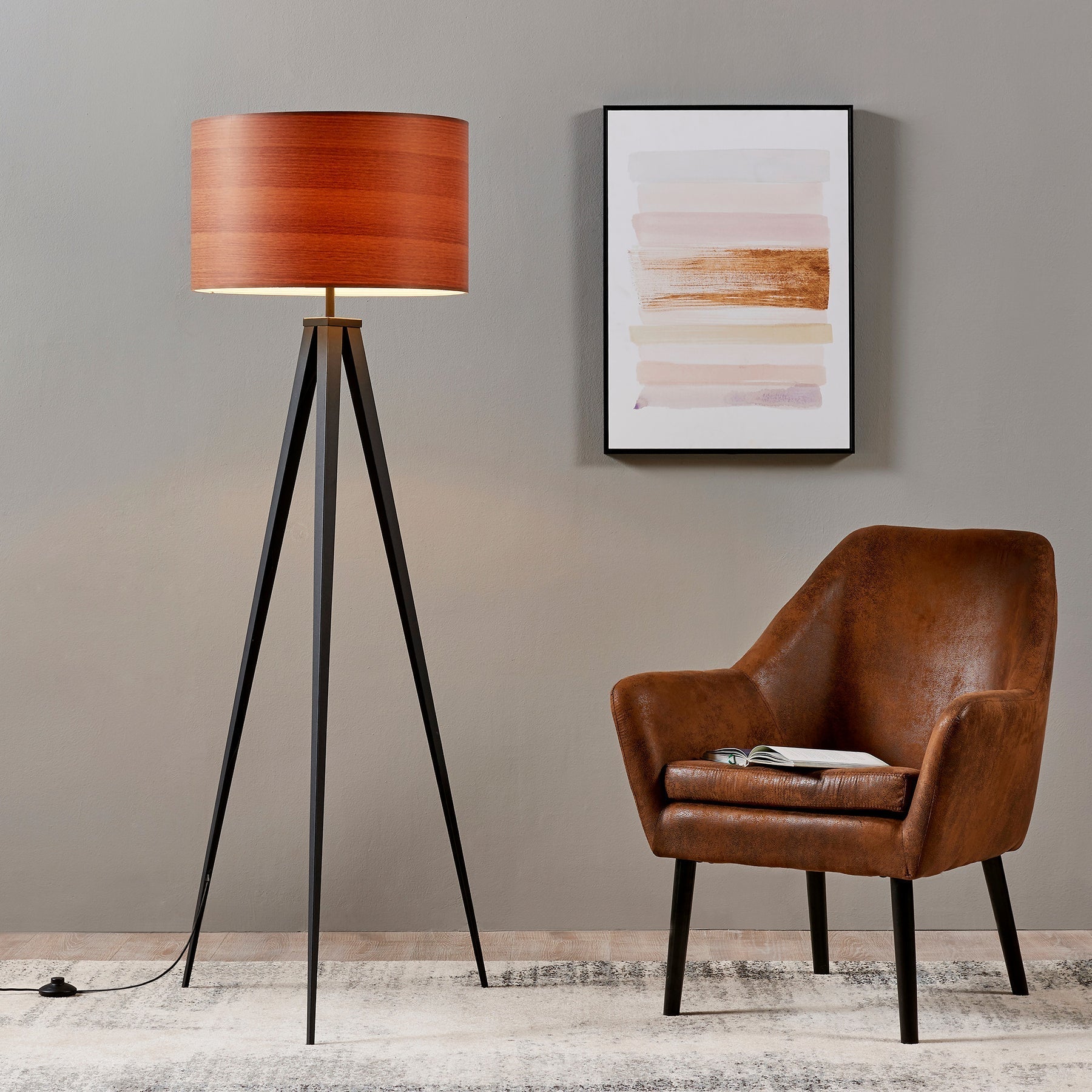 A Teamson set up with a beautiful leather chair and a tripod floor lamp.