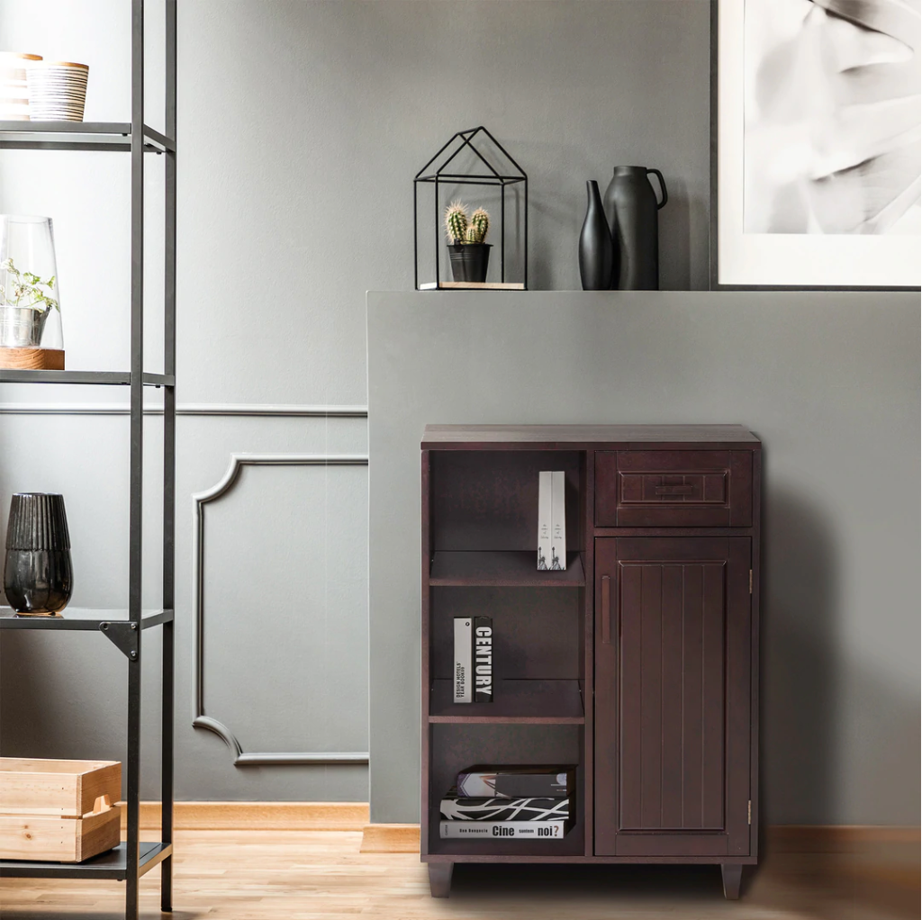 A dark brown floor cabinet with three open shelves and a drawer and a door against a gray wall.