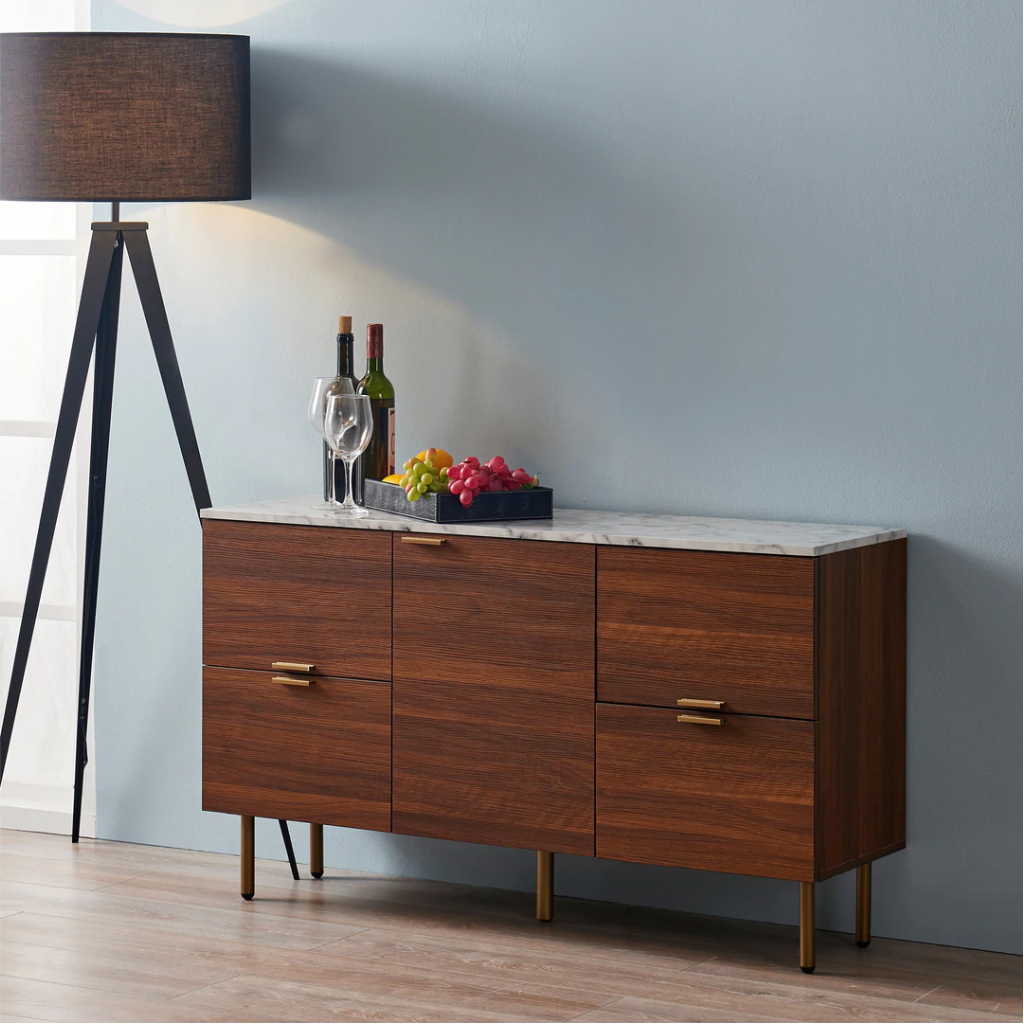 A rich walnut finished sideboard with a tripod floor lamp with a brown lamp shade against a blue wall.