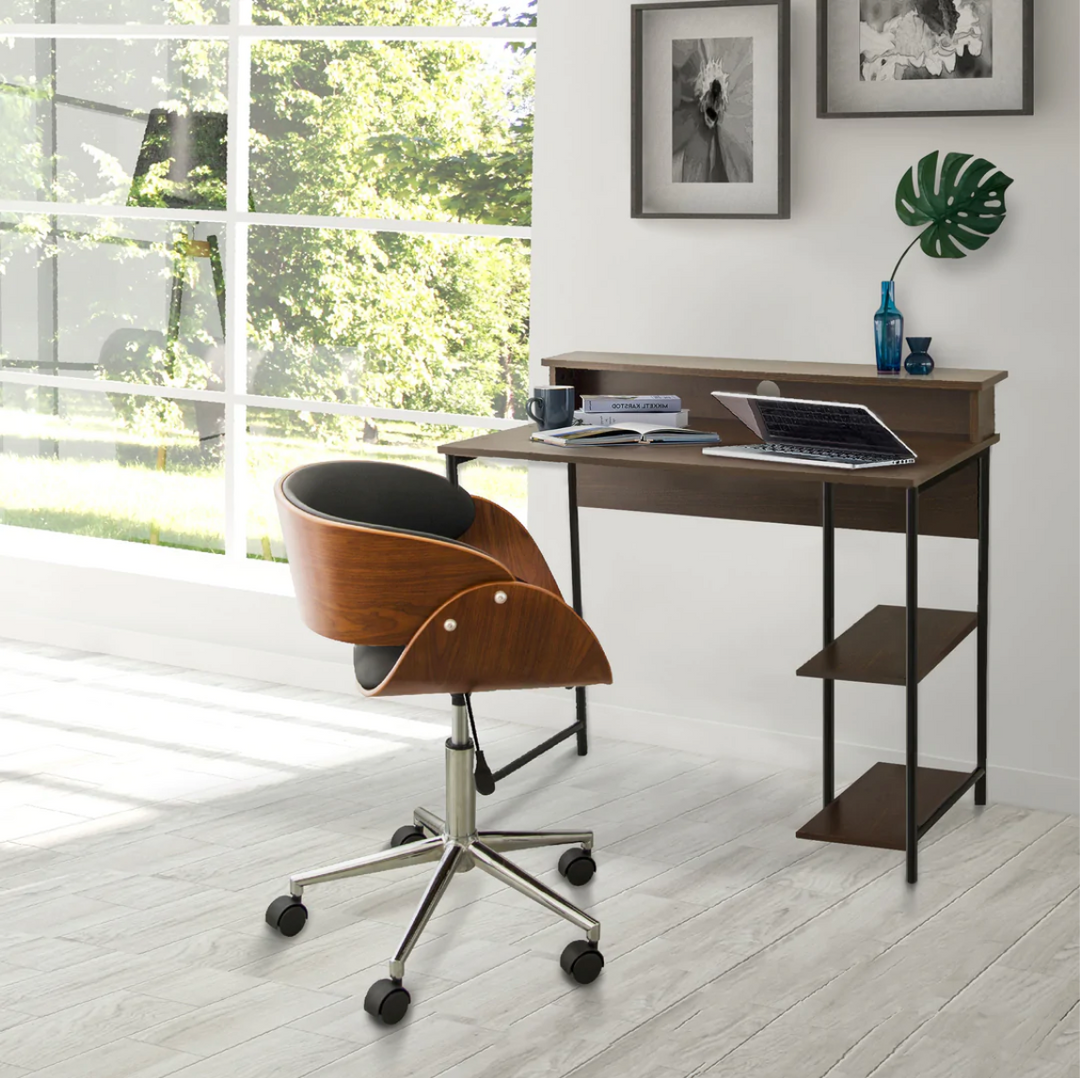 Brown roller chair sits infront of a writing style desk with a laptop and a plant on it against a white wall in a work from home office