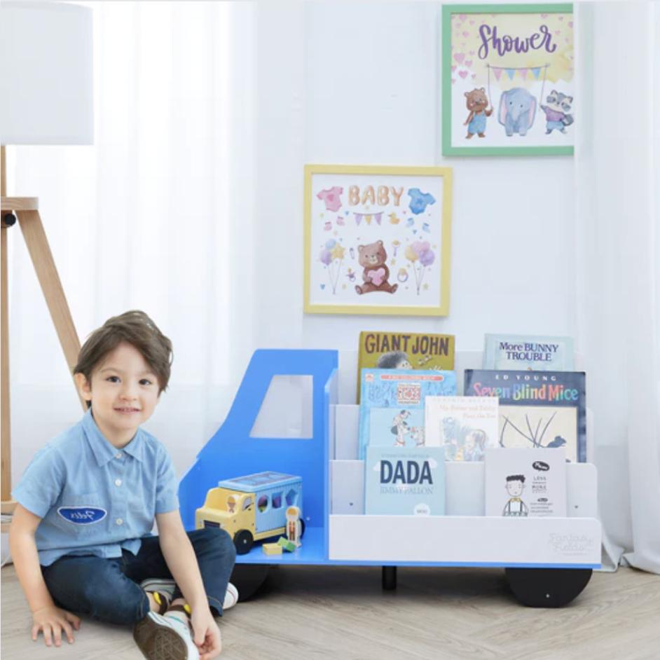 A smiling boy sits next to his truck themed display bookcase