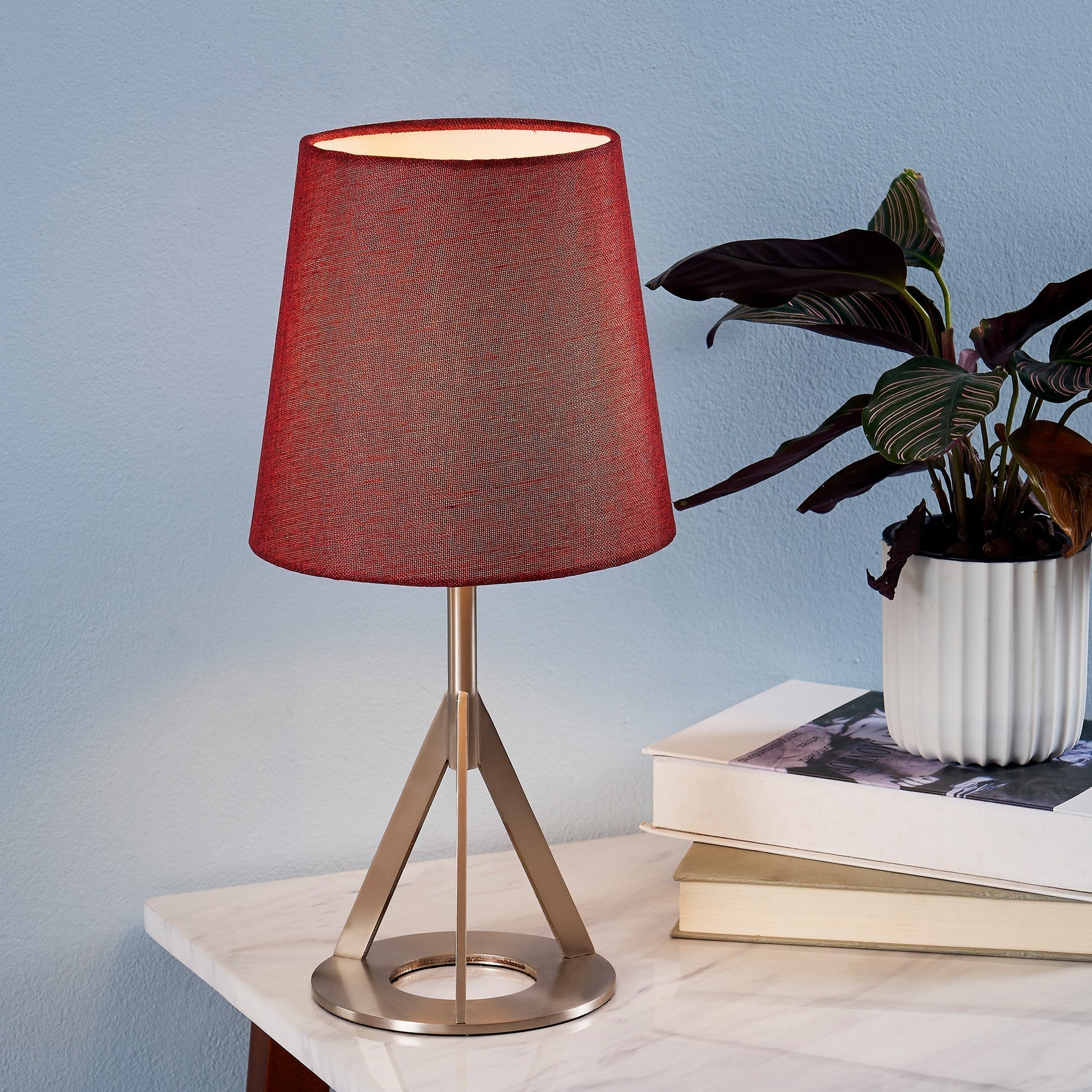 A red table lamp sits on top of a faux marble table.