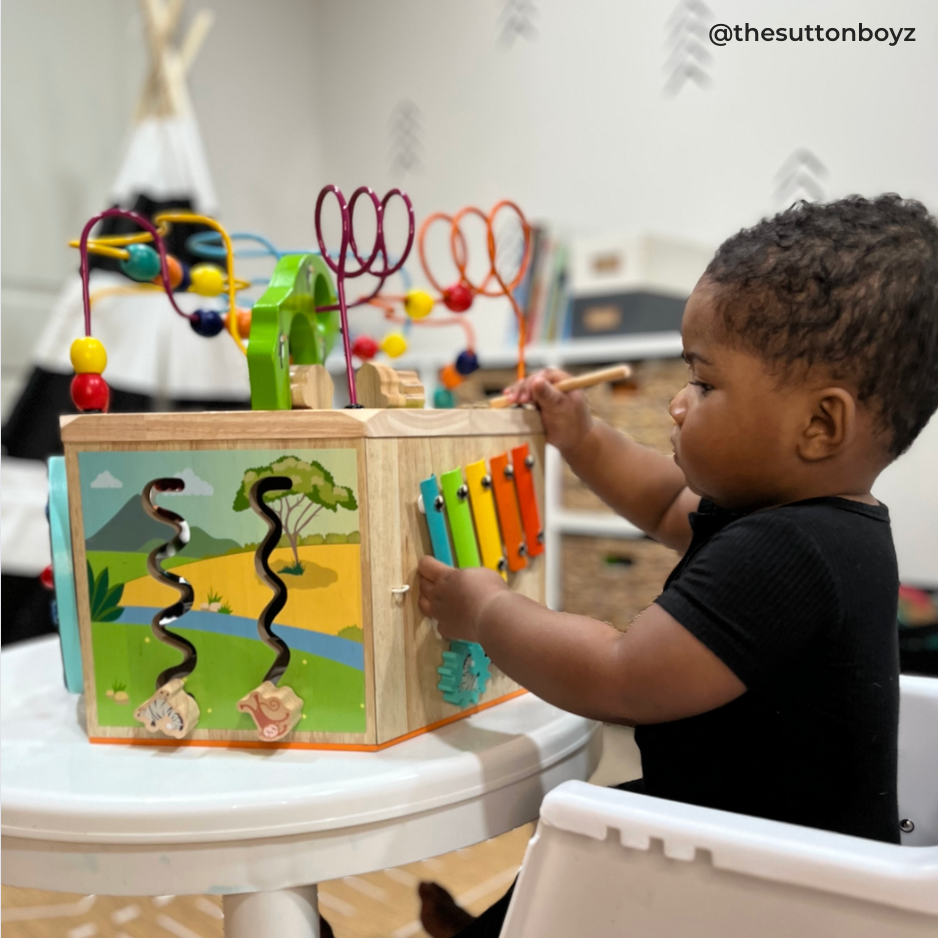 A young toddler plays with a wooden activity center for entertaining.