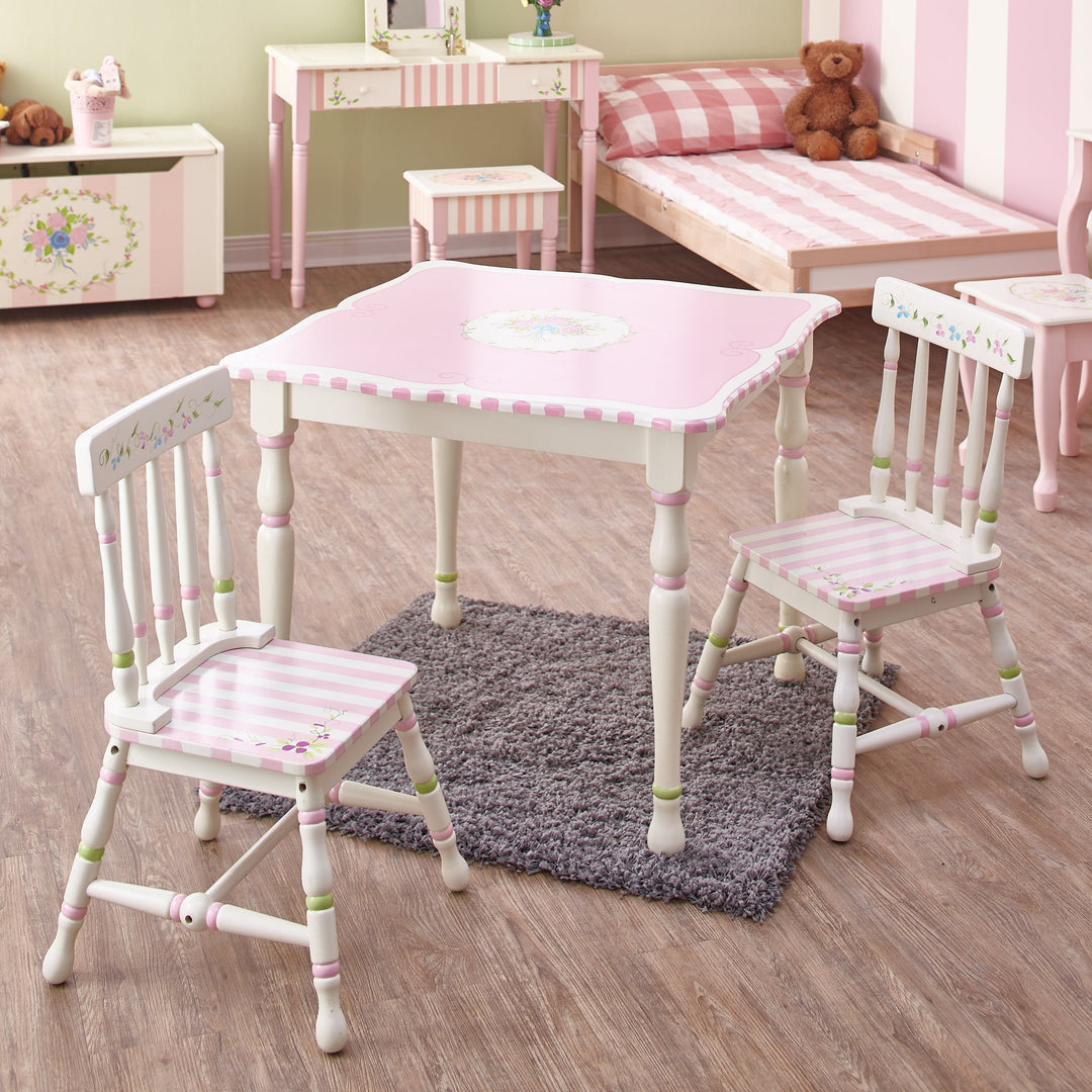 A child's room furnished with a vanity and stool, toy box, chairs and table decorated in white with pink stripes and floral accents