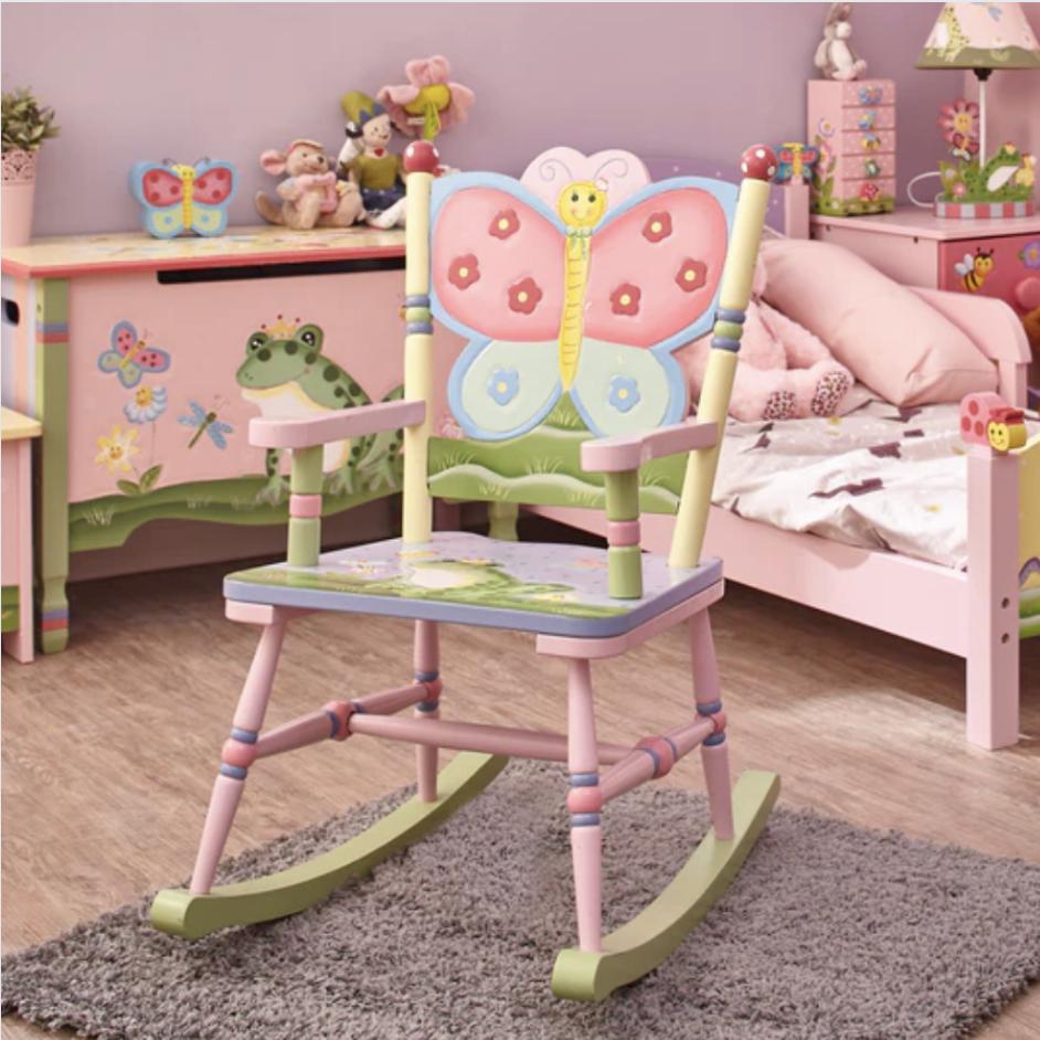 A child's rocking chair with lots of colors and a bold butterfly on the back is in a pink bedroom.