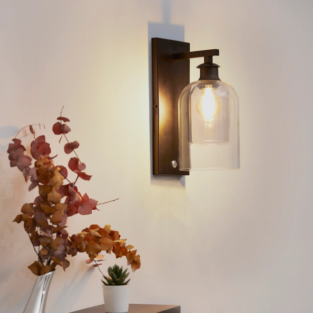 A modern black sconce light is mounted on a white wall