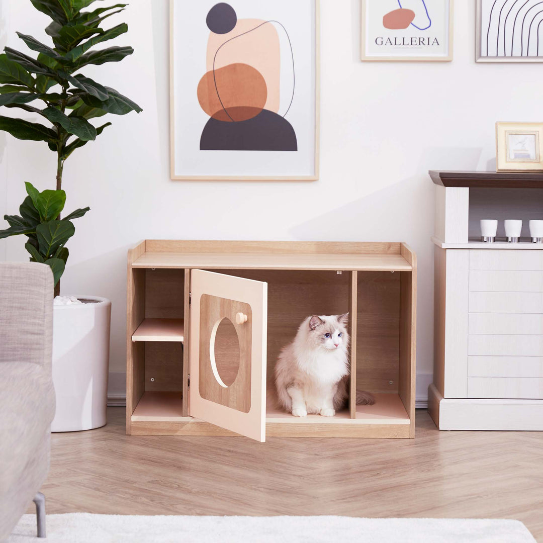 A fluffy cat sits at the door of alitter box enclosure with an oak finish in a white room