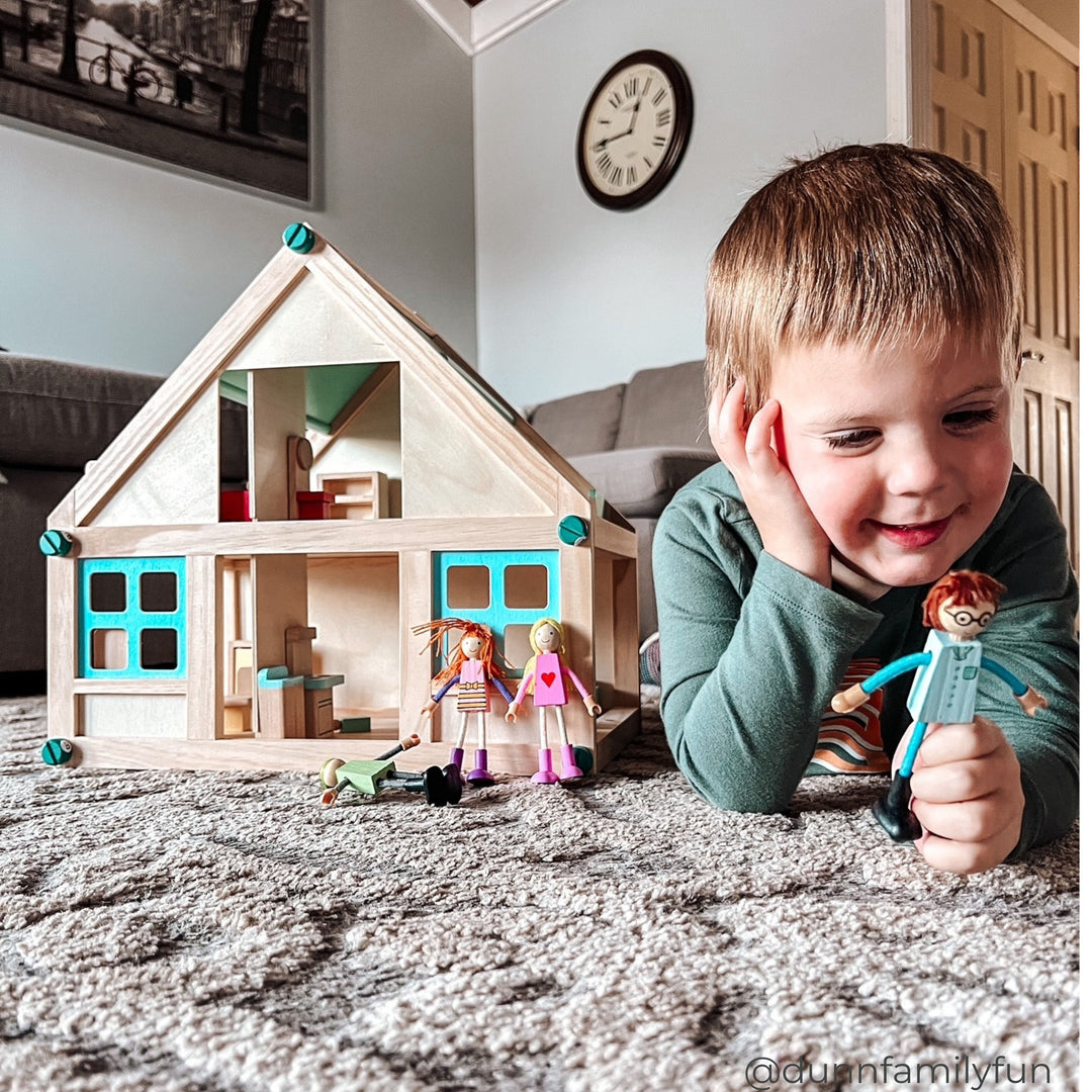 Young boy opening the drawers of a multi-colored play kitchen.