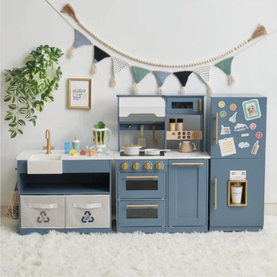 A gray play kitchen with beautiful gold hardware and realistic effects is displayed in a children's play room