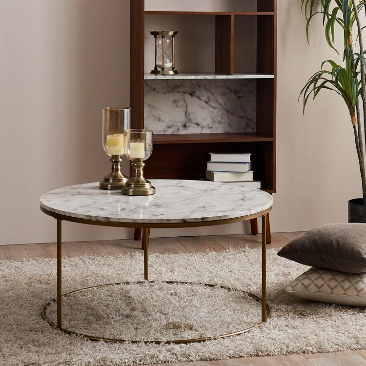 A faux marble coffee table sits in a stylish living room that also features a teamson bookcase in dark brown wood with a faux marble back.