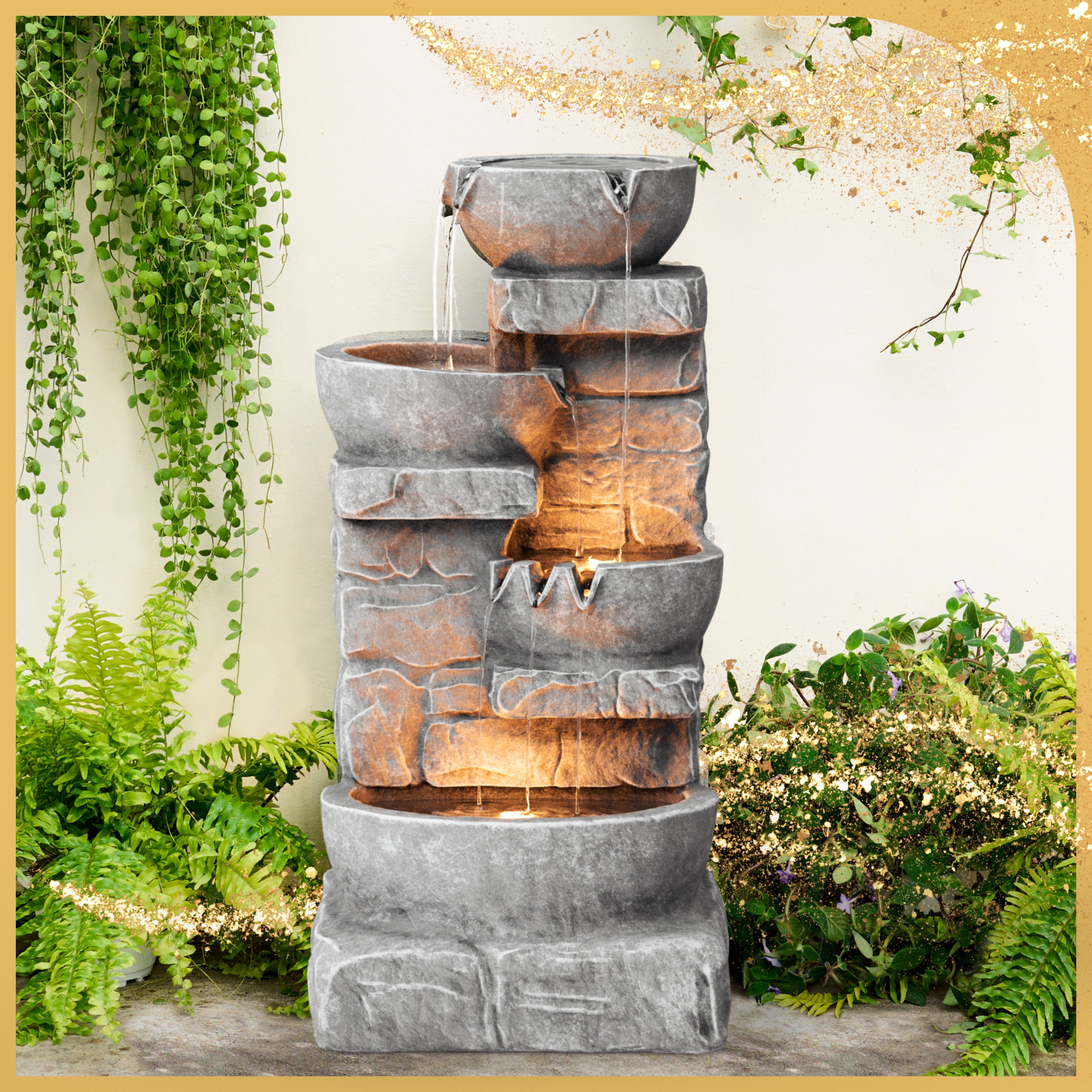 four bowls are stacked in faux stone, each trickling down to the next with a flow of water in an outdoor garden of ferns