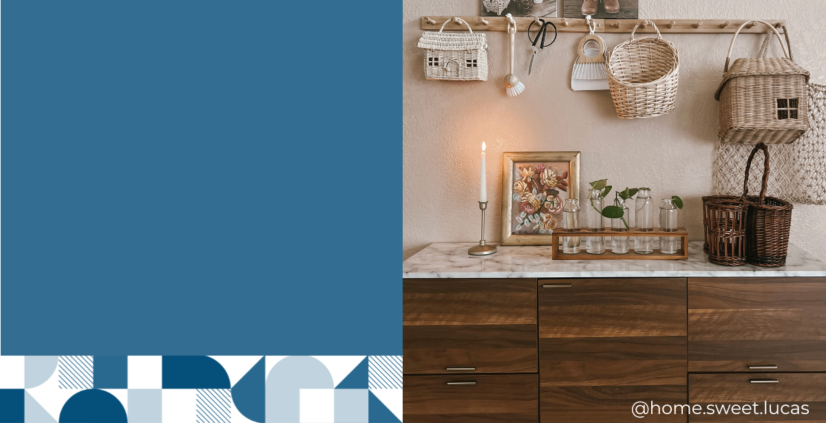 A brown side table with a faux marble top is decorated with warm brown and beige tones. The side table  has vases on top, a candle, a flower picture frame and wicker baskets. 