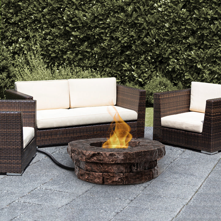 Outdoor seating arrangement with and a Teamson Home Outdoor Circular Stone-Look Propane Gas Fire Pit, Red-Brown.