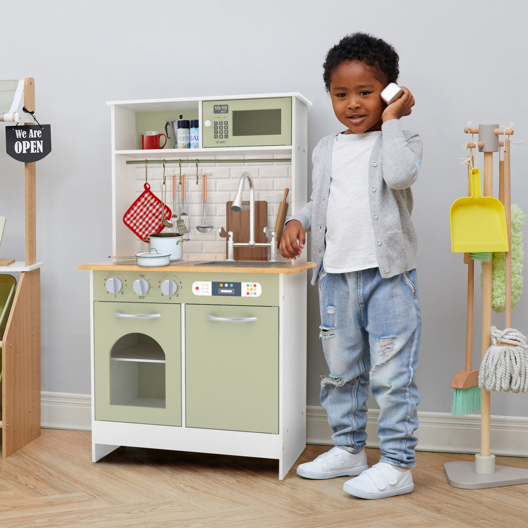 A child playing with a Teamson Kids Little Chef Boston Modern Wooden Kitchen Playset, White/Green that includes interactive features.