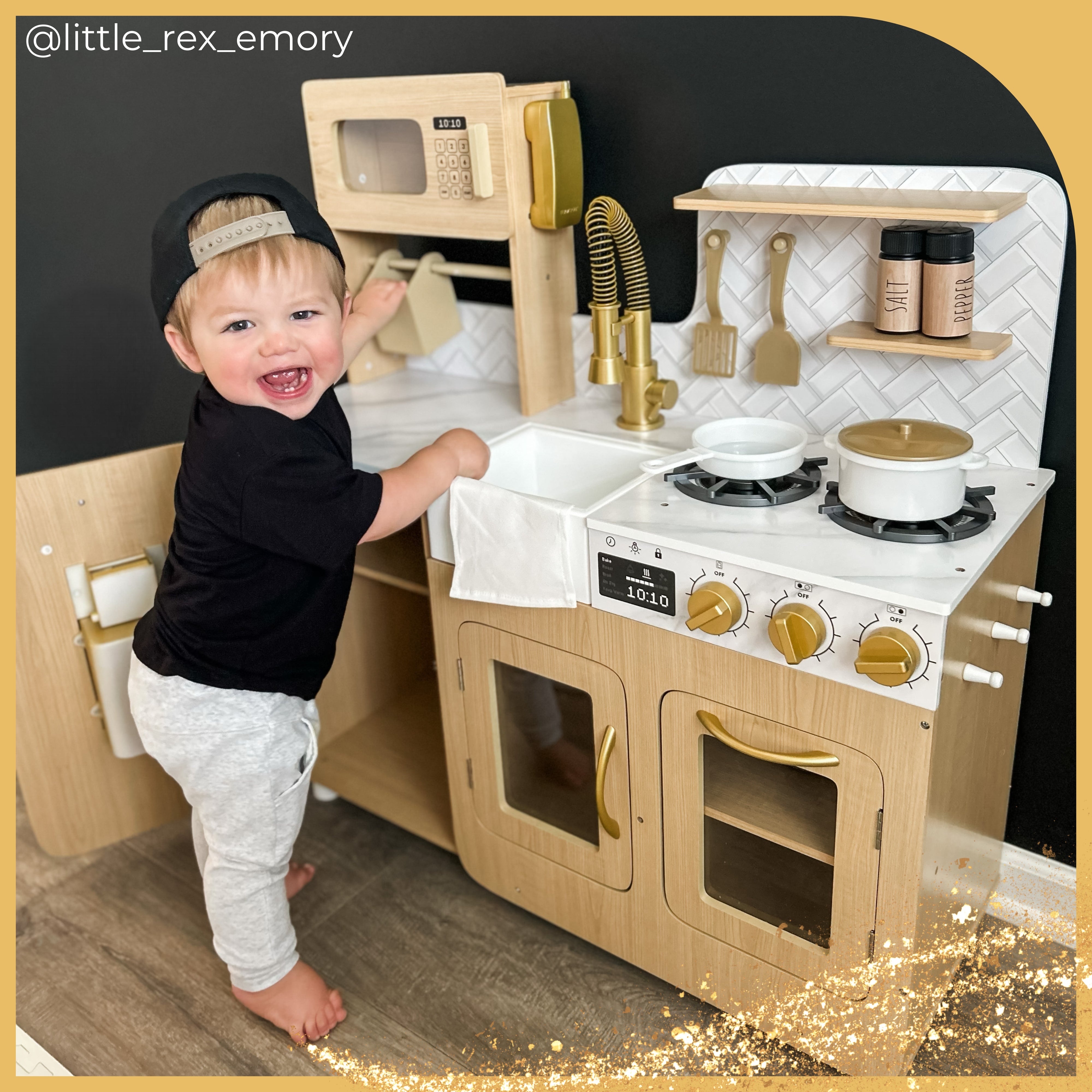 a toddler stands with a bright smile in front of the cyprus play kitchen