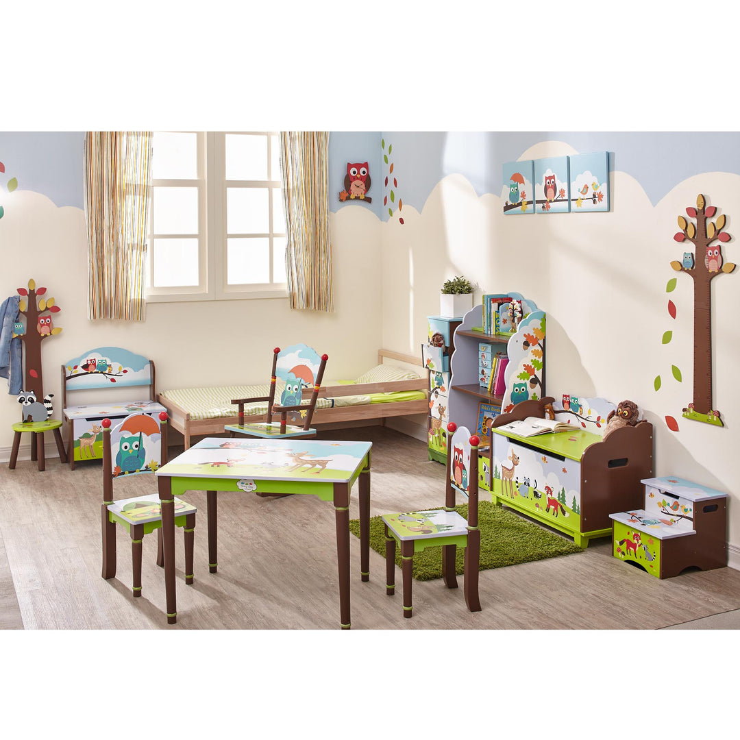 A children's room with multicolored Enchanted Woodland  decorated bedroom with a coat tree, toy box, rocking chair, set of drawers, bookshelf, storage bench, step stool, wall hangings and a table and chair set.