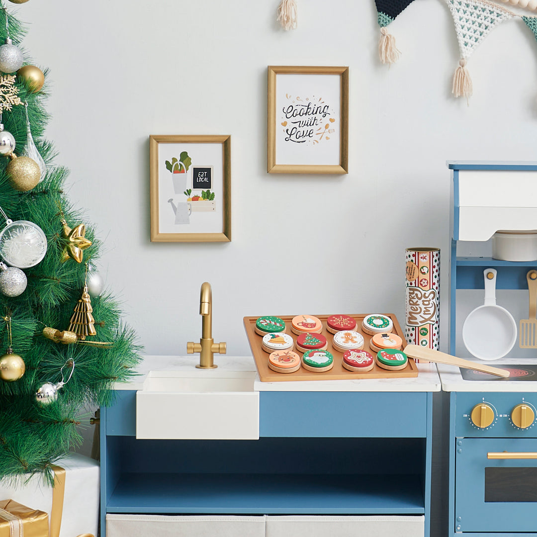 A child's play kitchen with festive decorations and a Teamson Kids - Cuttable Christmas Cookie Play Set on a countertop.