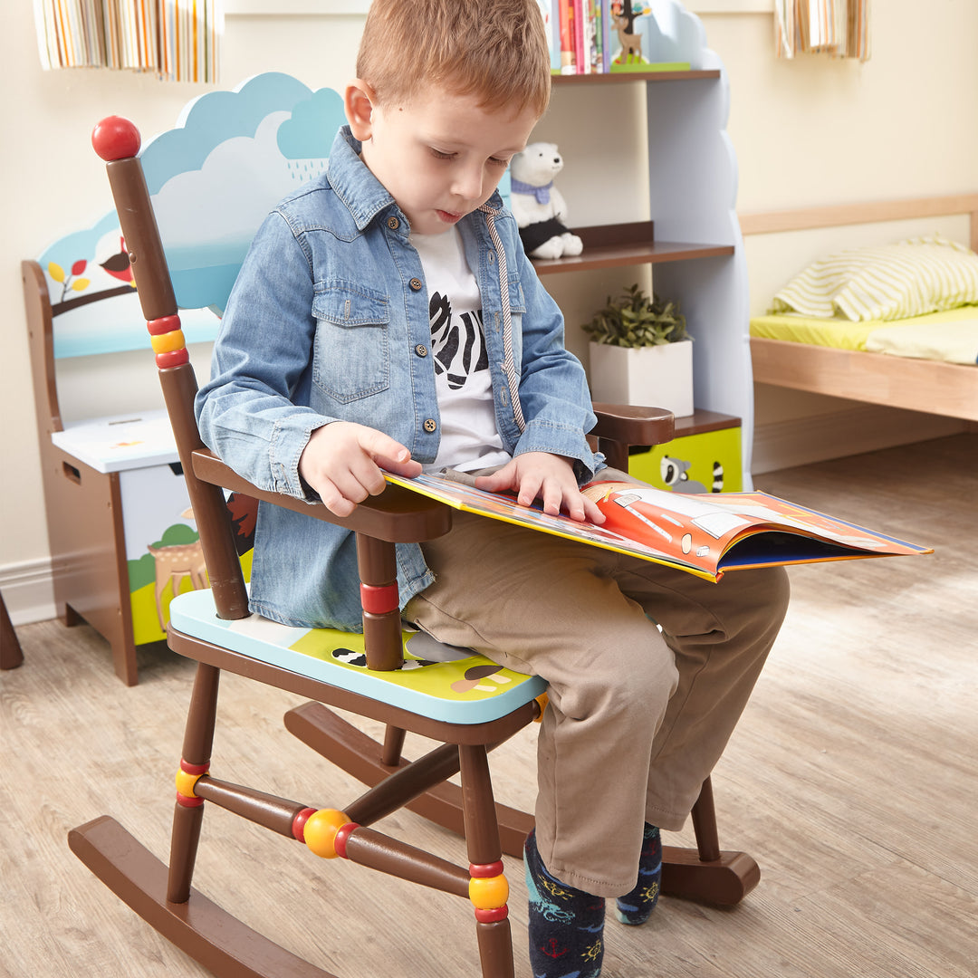 A boy is reading a book in a Fantasy Fields - Enchanted Woodland Rocking Chair, Multicolor.