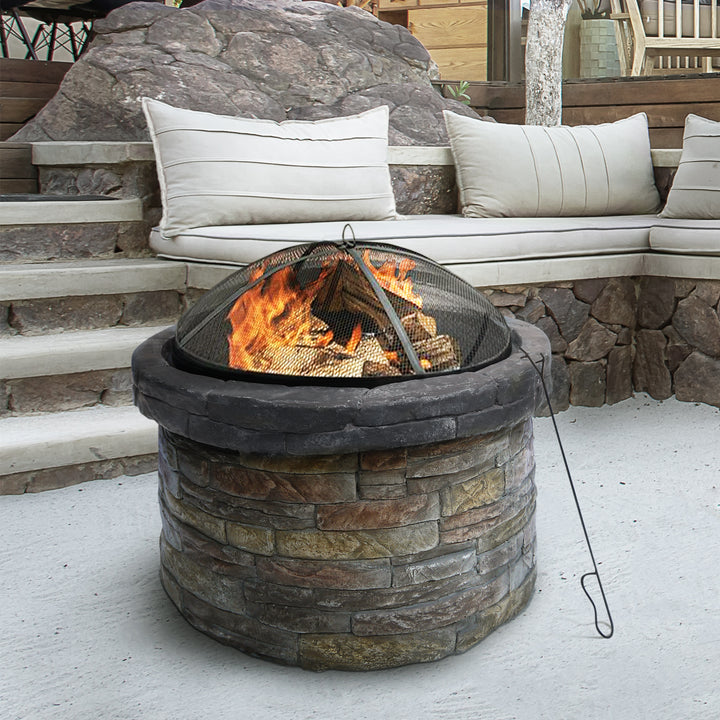 A Teamson Home 27" Outdoor Round Stone Wood Burning Fire Pit with Steel Base, Natural Stone on a patio near outdoor furniture enriches the outdoor decor.