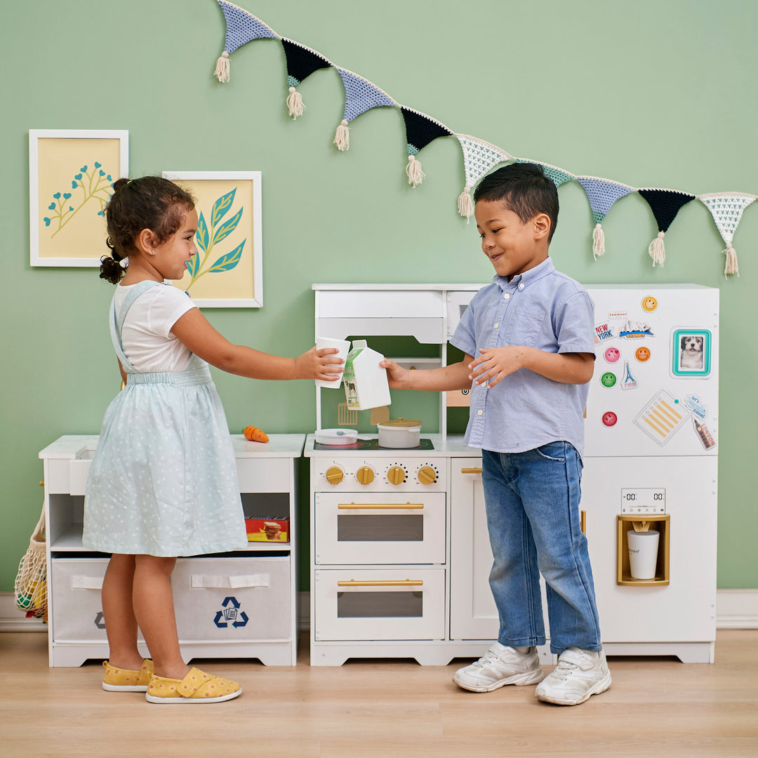 Two children playing with a Teamson Kids - Little Chef Atlanta Large Modular Play Kitchen, White/Gold.